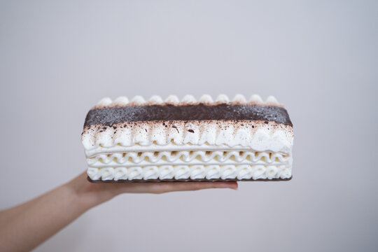 A rectangular piece of layered ice cream held in hand.
