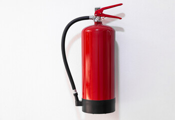 A red fire extinguisher hangs on a white wall.