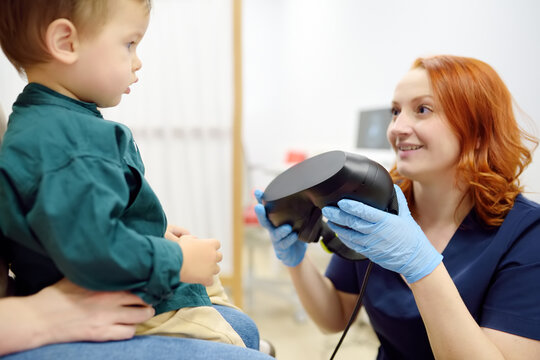Toddler boy with mom are at appointment with a pediatric neurologist. Neurology doctor is establishes contact and trust with the child. Doctor prepares to make positional testing of patient using VNG