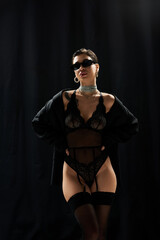 Obraz premium A young woman in black lace lingerie poses with a mysterious look in her eyes.