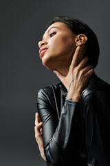 Woman in leather outfit poses sensually, looks up and left.