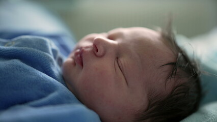 Serene newborn baby sleeping in a blue onesie, swaddled in soft blankets in a hospital bed, focus on the baby's peaceful expression, capturing the tranquility of newborn life