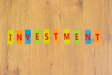 Investment symbol. Concept word Investment on beautiful colored paper. Beautiful wooden background. Business investment concept. Copy space.