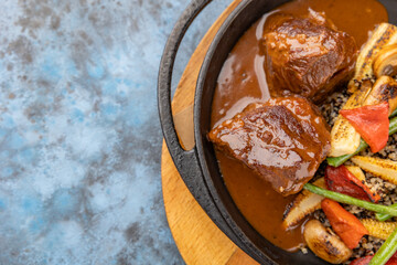Close up view on tasty goulash - grilled and roasted beef with corn cobs, asparagus, quinoa on hot pan. Restaurant food for lunch.