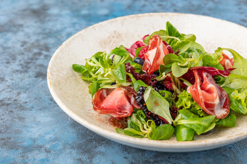 Tasty salad with ham and berries. Summer salad on a plate.