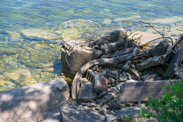 urban infrastructure waste (concrete pieces) partly submerged in water on a beach near the city