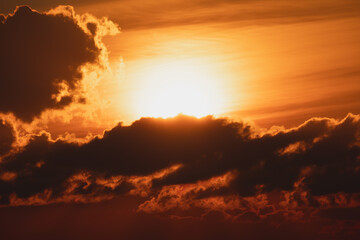 The sun behind the clouds during sunset, close-up photo taken with a telephoto lens.