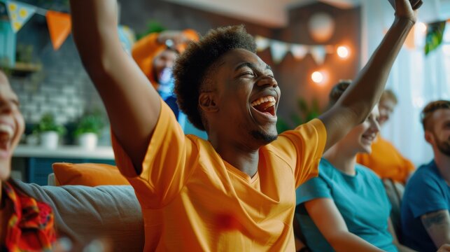 Multiracial, happy sports supporters cheering on their team while at home; spectators enjoying themselves while watching a tournament on TV; friends toasting to a team's achievement