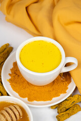 A traditional Ayurvedic drink with milk and turmeric in a white cup