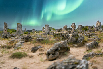 Stone formations under vibrant northern lights in a tranquil, remote landscape at night