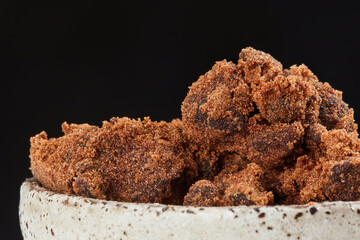 Cane sugar in a bowl on a black background. Shallow depth of field. Copy space	