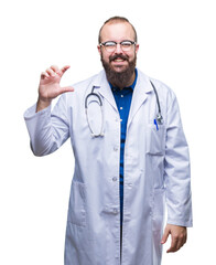 Young caucasian doctor man wearing medical white coat over isolated background smiling and confident gesturing with hand doing size sign with fingers while looking and the camera. Measure concept.