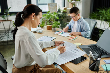 A mother works on a contract at her desk while her son with Down syndrome draws nearby.