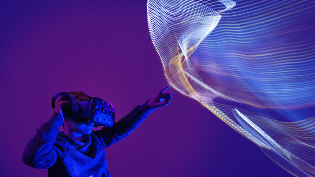 Kid with VR glasses points with the finger to virtuelle struktur hologramm universum. Kid with virtual reality glasses with virtuelle struktur bokeh.