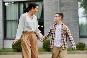 Obraz premium A mother walks hand-in-hand with her son down the street near an office building.