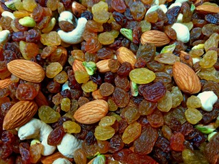 Assorted nuts, dry fruits, mix nuts, almond, cashew, pistachio, raisin pattern background. Variety nuts fruits raisins mix texture snack food background. Healthy vegan nuts raisin mix closeup top view