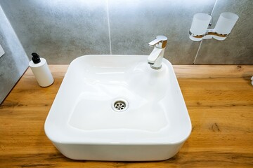 Fototapeta premium The white sink pairs beautifully with the wooden bathroom counter, creating a cohesive look that enhances the rooms appeal aesthetically and blends seamlessly with the surroundings