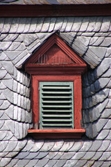 Attic dormer with louver shutter on the slate roof of a baroque city palace in the village of...