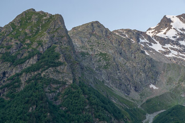 Obraz premium The formation of a glacier at the top of the mountain. Melting ice high in the mountains. A vacation trip to the mountains. Landscape with a view of the glacier. Snow-capped mountains in summer.