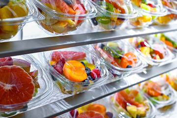 Boxes with pre-packaged fruit salads in a commercial fridge