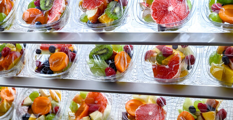 Boxes with pre-packaged fruit salads in a commercial fridge