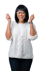 Beautiful young african american woman wearing glasses over isolated background excited for success with arms raised celebrating victory smiling. Winner concept.