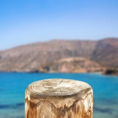 Fototapeta premium Wooden block, tree trunk as a table top with beautiful landscape of blue sea and mountain island in distance. Space for products and objects.