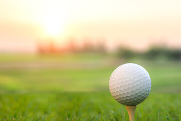 Golf ball placed on grass, background with bokeh and flare.