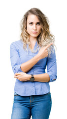 Obraz premium Beautiful young blonde business woman over isolated background Pointing with hand finger to the side showing advertisement, serious and calm face