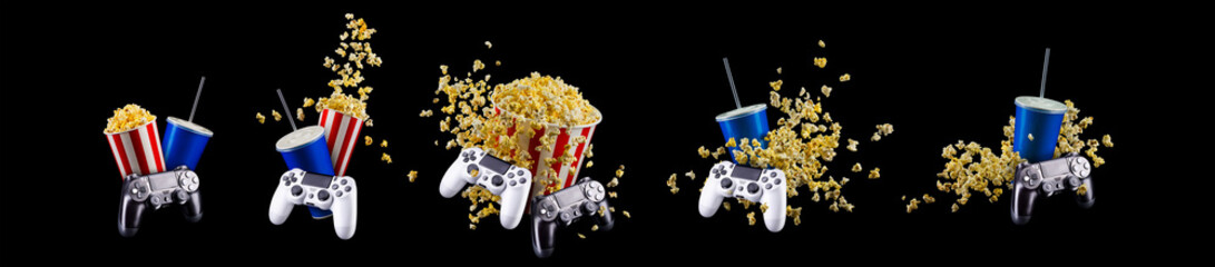 Paper bucket with popcorn, cup of drink and video game joystick on black