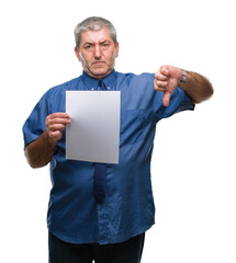 Handsome senior man holding blank sheet paper over isolated background with angry face, negative sign showing dislike with thumbs down, rejection concept