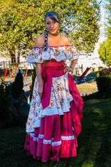 latin woman with brown skin posing and looking at the camera in a colorful folkloric dress from tarija bolvia - dance concept