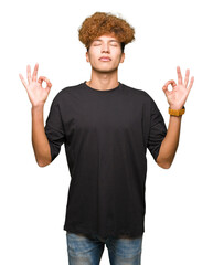 Young handsome man with afro hair wearing black t-shirt relax and smiling with eyes closed doing meditation gesture with fingers. Yoga concept.