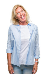 Middle age blonde woman over isolated background sticking tongue out happy with funny expression. Emotion concept.