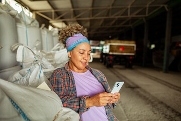 Female farmer using smartphone in barn