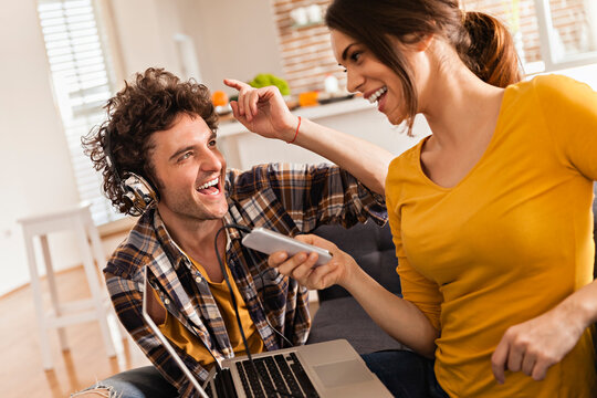 Happy couple laughing and listening to music at home