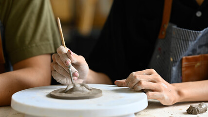 Close-up of a boy's hands delicately decorating patterns on clay, showcasing focus and creativity in pottery making, highlighting the intricacy of the art form, Crafts and DIY with people concept