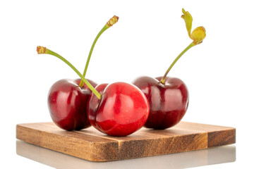Three sweet cherries with wooden tray, macro, isolated on white background.
