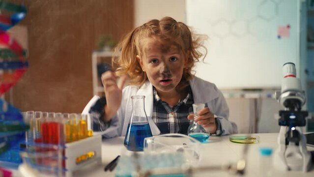 Funny girl in lab coat holds lab flask, explosion after experiment, fun science