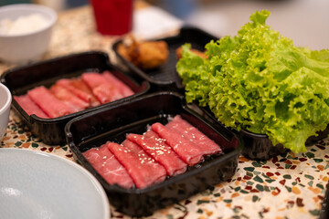 Fresh sliced shabu meat place in a row on a black tray. 