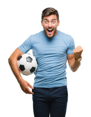 Young handsome man holding soccer football ball over isolated background screaming proud and celebrating victory and success very excited, cheering emotion