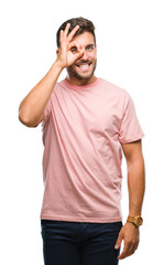 Young handsome man over isolated background doing ok gesture with hand smiling, eye looking through fingers with happy face.