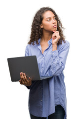 Young hispanic woman holding computer laptop serious face thinking about question, very confused idea