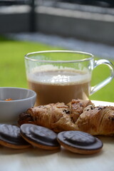 Delicious fresh sweet breakfast croissant with jam marmalade and coffee outside on patio garden