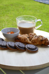 Delicious fresh sweet breakfast croissant with jam marmalade and coffee outside on patio garden