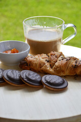 Delicious fresh sweet breakfast croissant with jam marmalade and coffee outside on patio garden