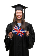 Young hispanic woman wearing graduated uniform holding flag of united kingdom with a happy face standing and smiling with a confident smile showing teeth