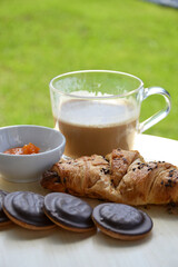 Delicious fresh sweet breakfast croissant with jam marmalade and coffee outside on patio garden