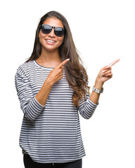 Young beautiful arab woman wearing sunglasses over isolated background smiling and looking at the camera pointing with two hands and fingers to the side.