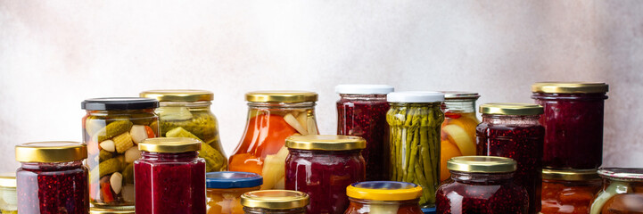 Preserving vegetables for the winter, a lot of glass jars with canned vegetables and adjika, jam and vegetable salads, pickled or fermented vegetables, banner